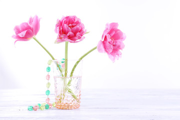 Obraz premium Pink tulips in glass vase with beads isolated on white