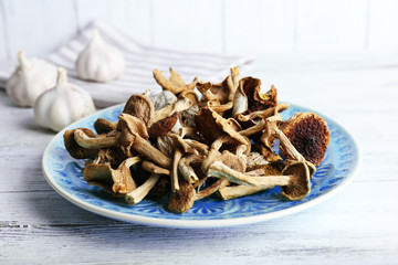 Dried mushrooms in plate on wooden background
