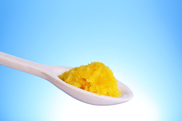 Laboratory spatula with granules on blue background