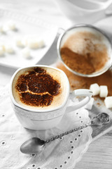 Cup of latte coffee art on wooden table, on light background