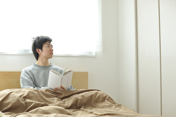 ベッドの上で眠そうにしているパジャマ姿の男性