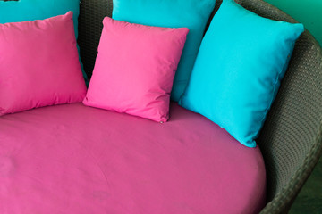 pink and blue pillow on brown rattan sofa