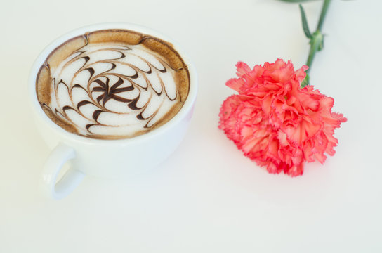 a cup of latte art and carnation on white background