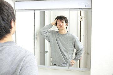 Fototapeta premium 朝起きて自宅の洗面台の鏡に映る眠そうな自分を見つめる日本人男性