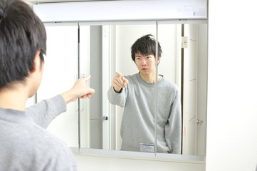 Fototapeta na wymiar 朝起きて自宅の洗面台の鏡に映る眠そうな自分を見つめる日本人男性