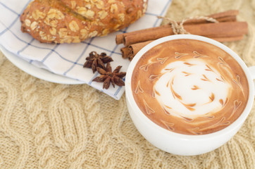 A cup of coffee with latte art and croissant on a knitted  backg