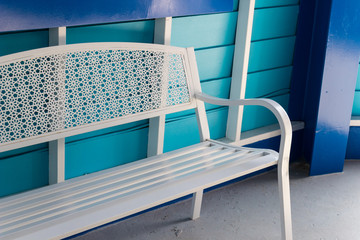 Fototapeta premium white metal seat beside blue wall
