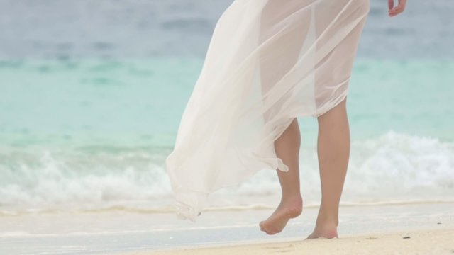 Legs of an beautiful woman walking on the sandy Maldives beach. 