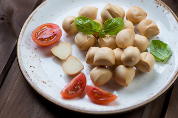 Provoletta cheese with green basil leaves and tomatoes, close-up