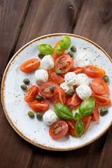 Above view of caprese salad with caper berries, selective focus