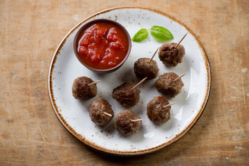 Meatballs on skewers with dipping sauce, high angle view