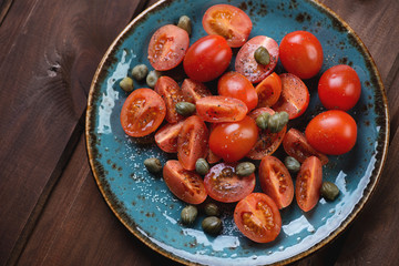 Above view of cherry tomatoes with capers, sea salt and pepper