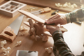 Craftsman building a wooden toy airplane