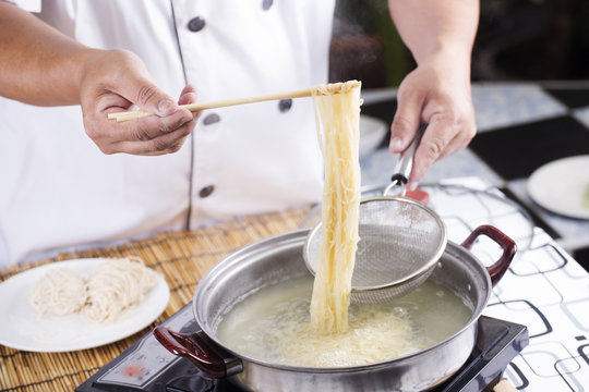Chef holding colander with cooked Noodle