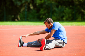 Young man stretching body, warming up for jogging