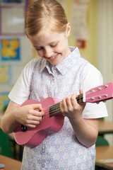 Girl Learning To Play Ukulele In School Music Lesson
