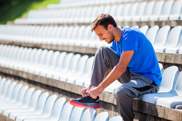 Young man tying a shoelace before jogging