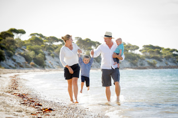young playful family walking on beach enjoying summer holidays