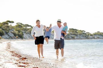 young happy family walking on beach enjoying summer holidays