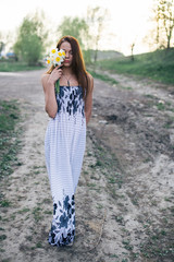 Red-haired young lady with bouquet of daffodils at countryside