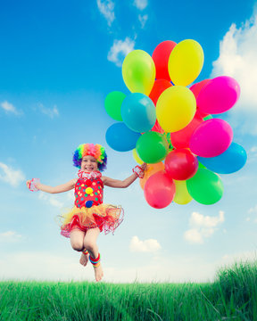 Child with toy balloons in spring field