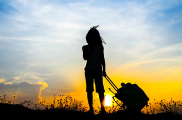 Silhouette Girl with a suitcase with sun set.