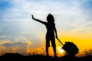 Silhouette Girl with a suitcase with sun set.