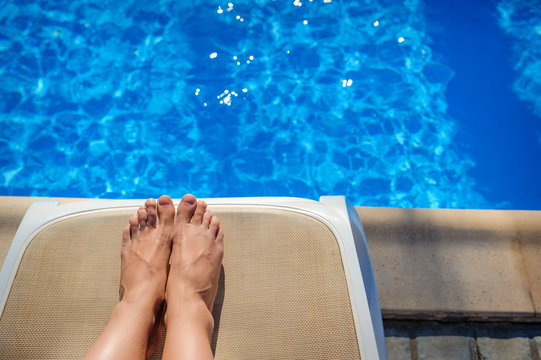 Tanned legs girls closeup on a lounger by the pool