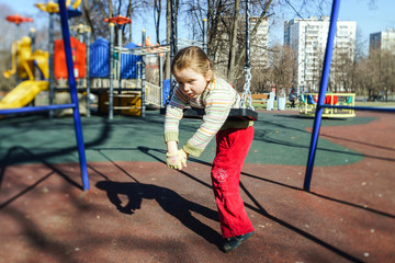 Fototapeta na wymiar Cute little girl swinging seesaw on children playground