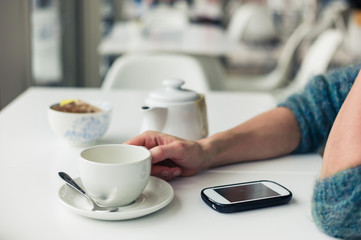 Woman using phone and having tea