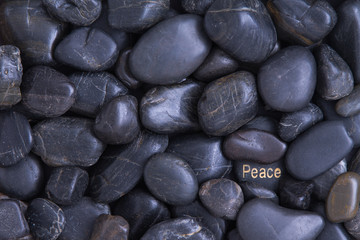 Fototapeta na wymiar Black pebble background with a Peace theme