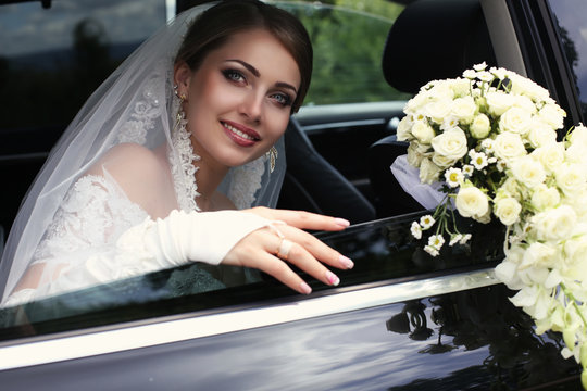  Bride In Wedding Dress With Bouquet Of Flowers Posing In Car