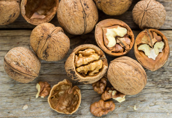 Walnut kernels and whole walnuts on rustic old wooden table
