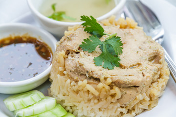 Rice roast chicken with spoon and fork on white plate.