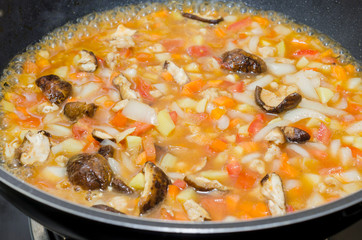 cooking pasta with chicken and meat gravy on stove