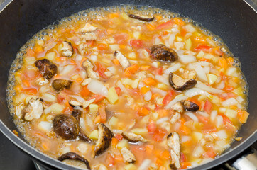 cooking pasta with chicken and meat gravy on stove