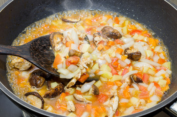 cooking pasta with chicken and meat gravy on stove