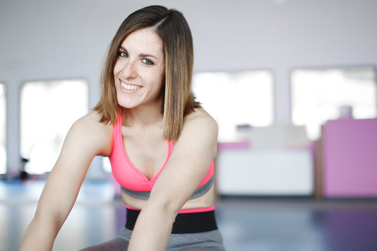 smiling woman doing exercises on mat in gym