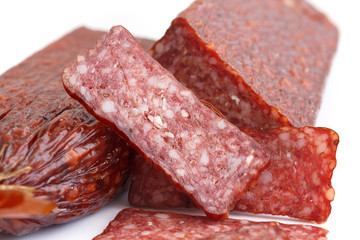 Premium salami, cut, sliced on white. Macro.
