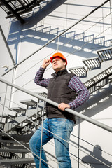 male worker in hardhat standing on steel staircase