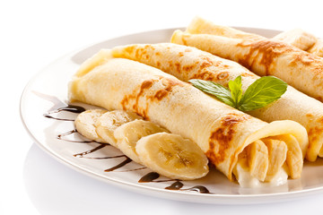 Crepes with bananas and cream on white background