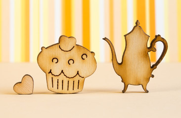 Wooden icons of cake and teapot with little heart on orange stri