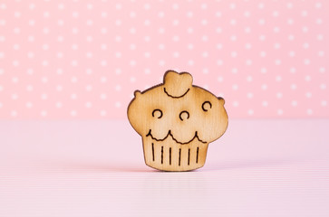 Wooden icon of cake on pink background