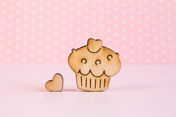 Wooden icon of cake with little heart on pink background