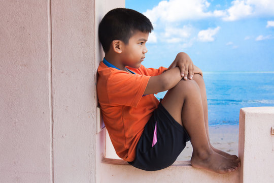 boy sad siting along on beach and blue sky background