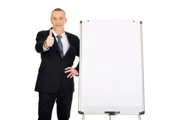 Male executive with ok sign near flip chart