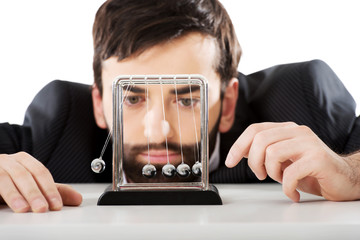 Man moving newton balls in office.