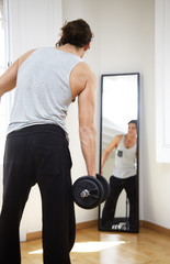 Fototapeta na wymiar man with a dumbbells in sunny flat with mirror