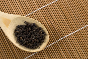 Black Pepper in a Wood Spoon on Bamboo
