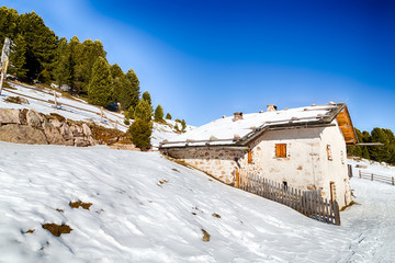 High-altitude mountain hut among snow-capped peaks and pine fore